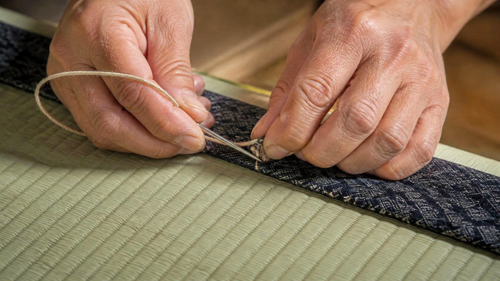 畳職人の手元。畳針と糸で畳の縁を縫っている（イメージ）
